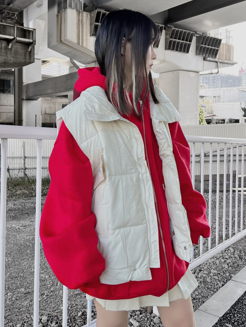 ホワイト系のスニーカー、ホワイト系のベスト、レッド系のパーカーを着用したレディースの冬コーディネートの2枚目の写真