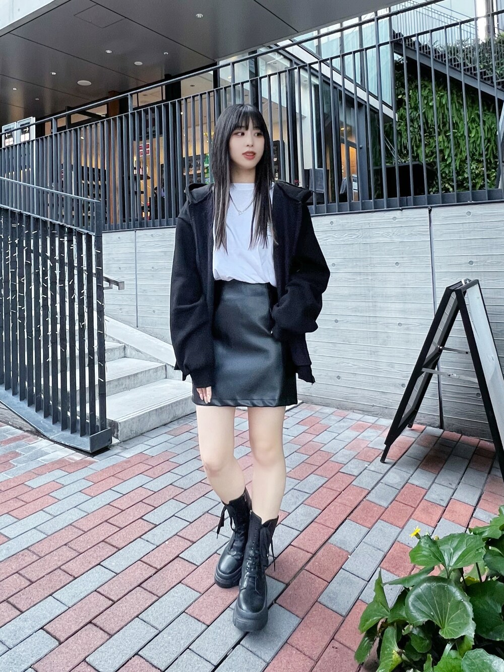 ブラック系のパーカー、ブラック系のスカート、ブラック系のブーツを着用したレディースの冬コーディネートの2枚目の写真