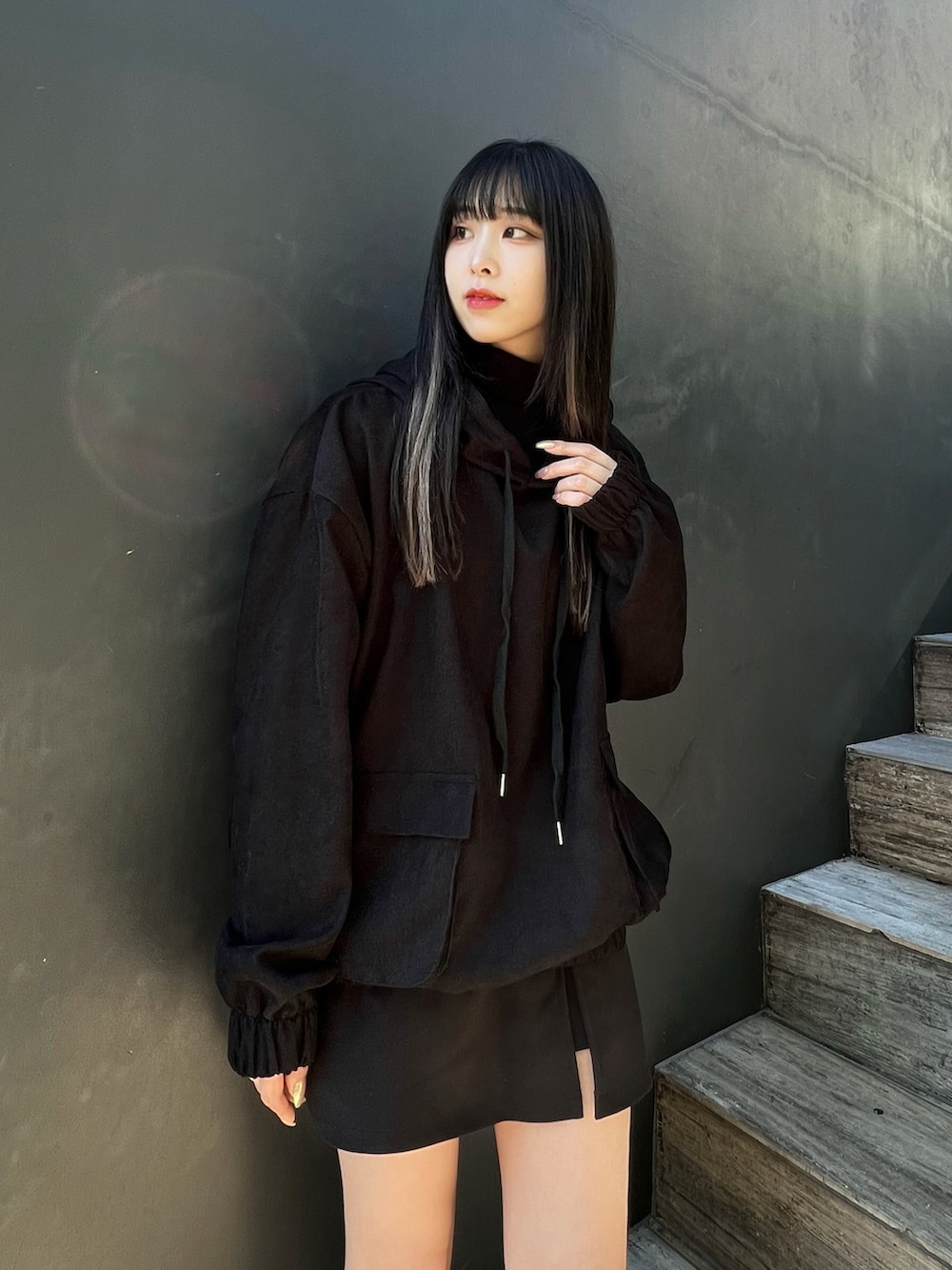 ブラック系のパーカー、ブラック系のスカート、ブラック系のブーツを着用したレディースの冬コーディネートの2枚目の写真