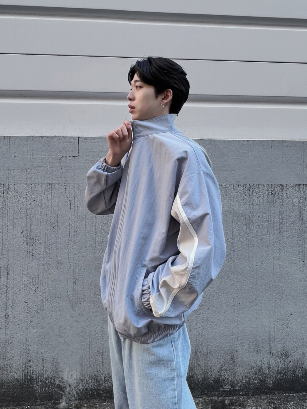 ブルー系のナイロンジャケット、ブルー系のデニムパンツ、ホワイト系のスニーカーを着用したメンズの春コーディネートの3枚目の写真