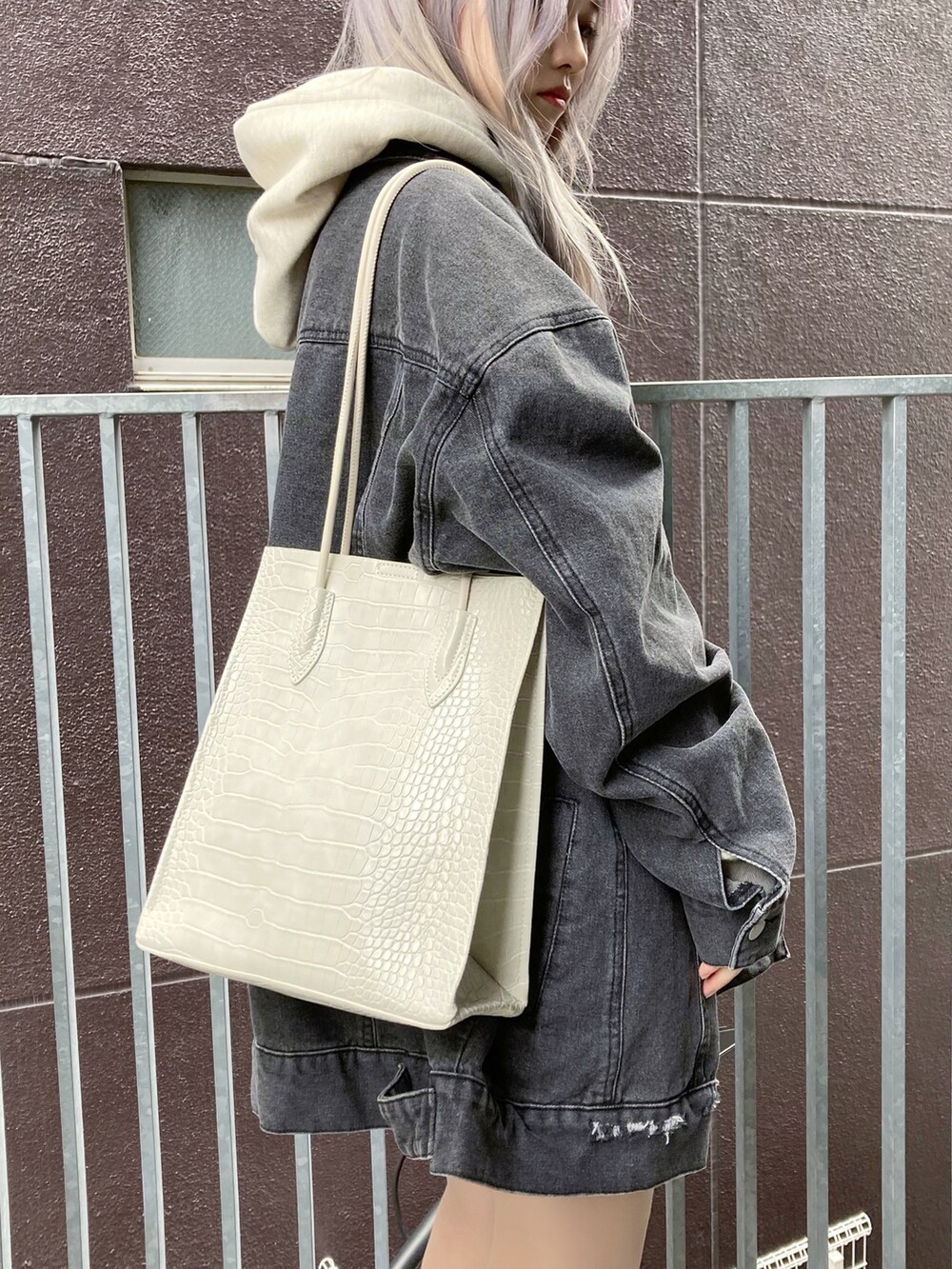 ホワイト系のトートバッグ、ベージュ系のパーカー、ホワイト系のスニーカーを着用したレディースの冬コーディネートの2枚目の写真