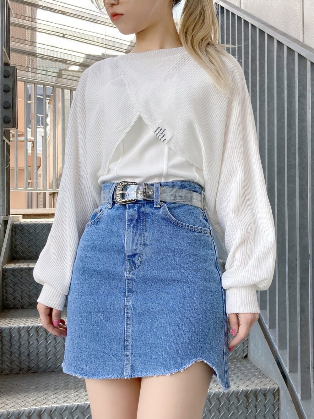 ホワイト系のニット/セーター、ホワイト系のタンクトップ、ブルー系のデニムスカートを着用したレディースの春コーディネートの2枚目の写真