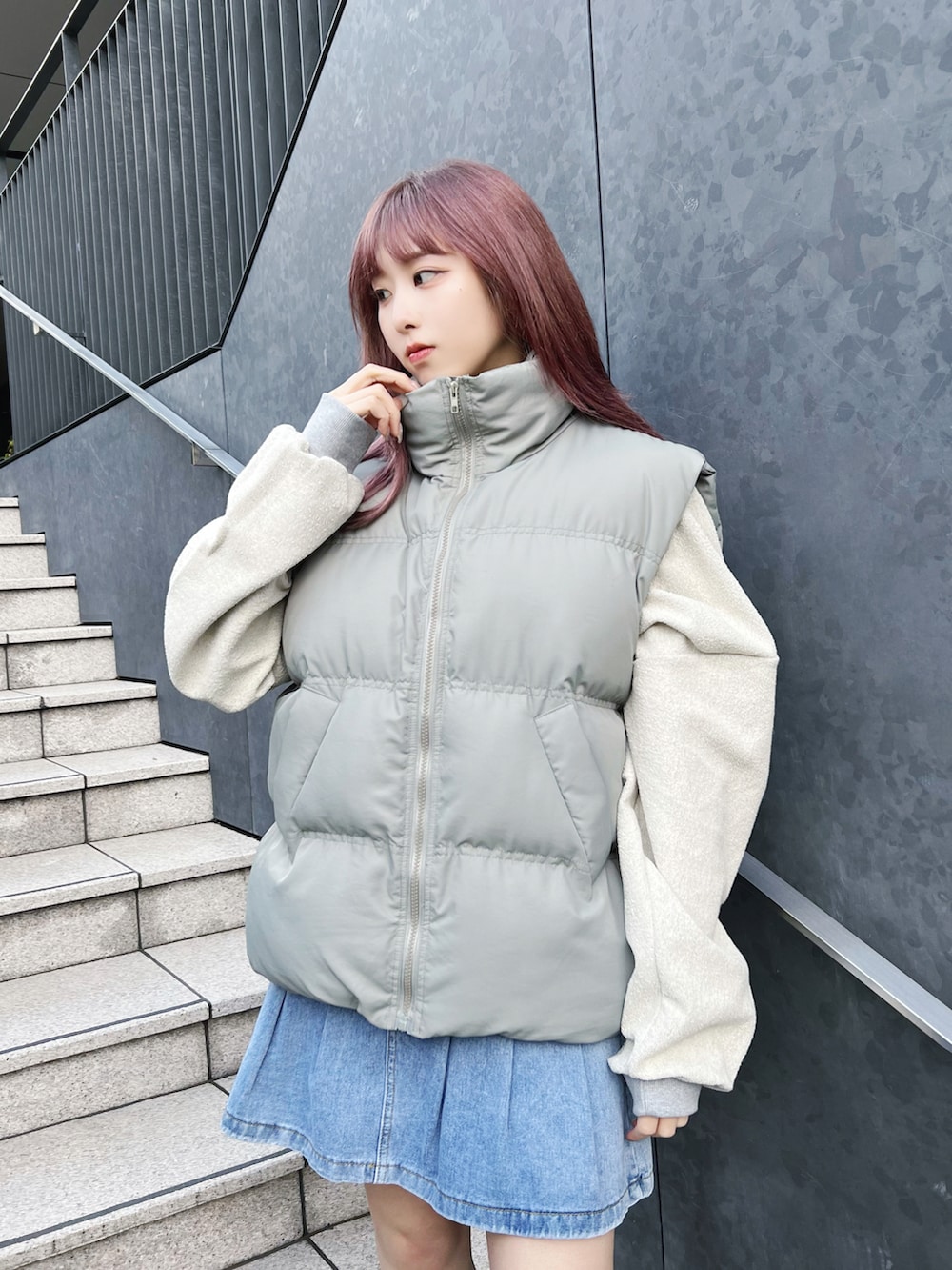 グリーン系のダウンベスト、グレー系のスウェット、ブルー系のデニムスカートを着用したレディースの冬コーディネートの3枚目の写真