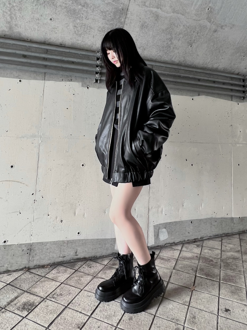 グレー系のニット/セーター、ブラック系のライダースジャケット、ブラック系のスカートを着用したレディースの冬コーディネートの2枚目の写真