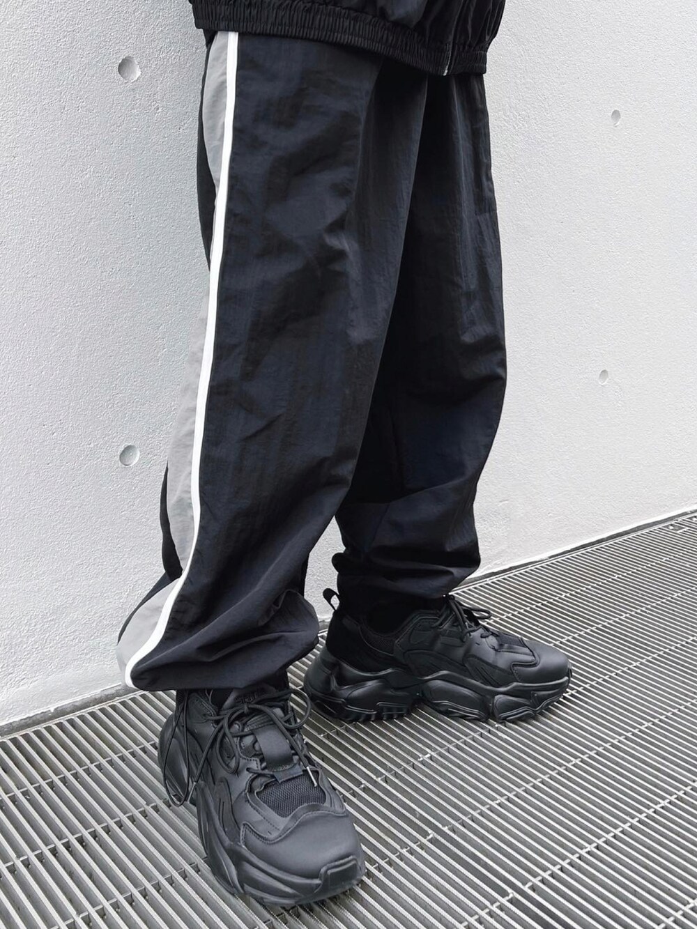 ブラック系のナイロンジャケット、ブラック系のその他パンツ、ブラック系のスニーカーを着用したメンズの冬コーディネートの3枚目の写真