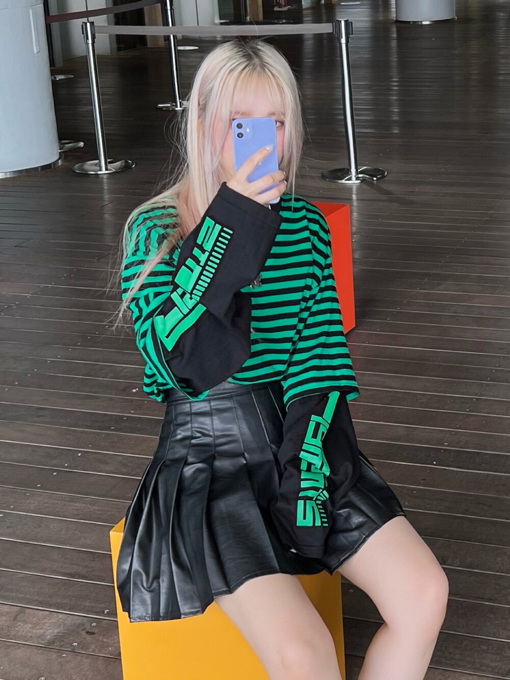 ブラック系のスカート、グリーン系のTシャツ/カットソー、ブラック系のブーツを着用したレディースの秋コーディネートの2枚目の写真