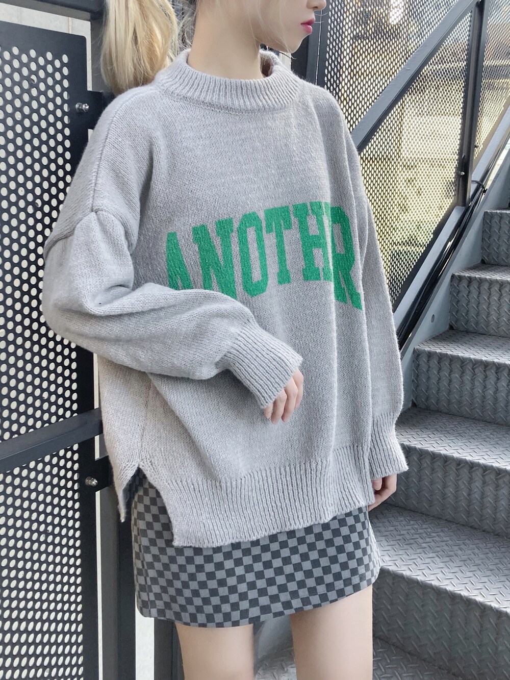 グレー系のニット/セーター、ブラック系のスカート、ブラック系のスニーカーを着用したレディースの冬コーディネートの2枚目の写真