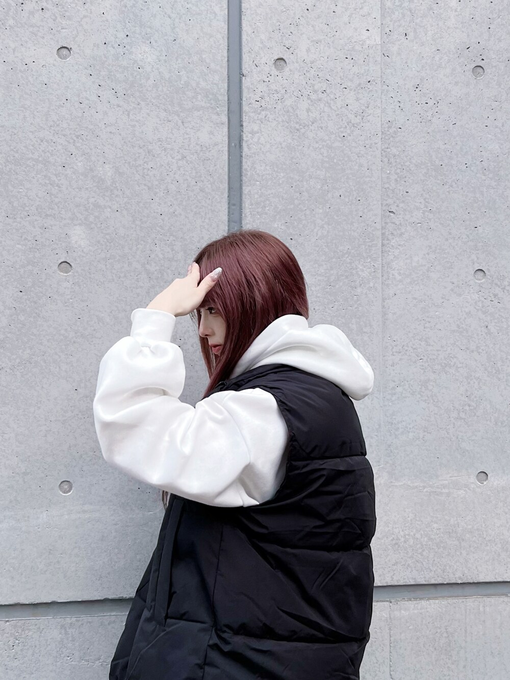 ブルー系のデニムパンツ、ブラック系のダウンベスト、ホワイト系のパーカーを着用したレディースの冬コーディネートの2枚目の写真