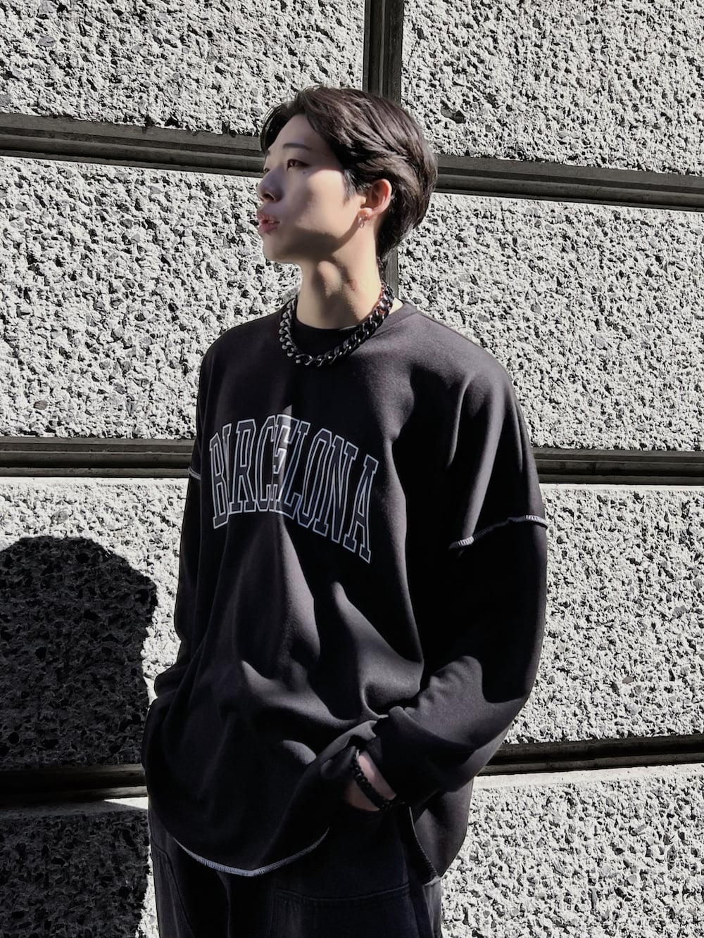 ブラック系のTシャツ/カットソー、ブラック系のスニーカー、ブラック系のデニムパンツを着用したメンズの春コーディネートの3枚目の写真