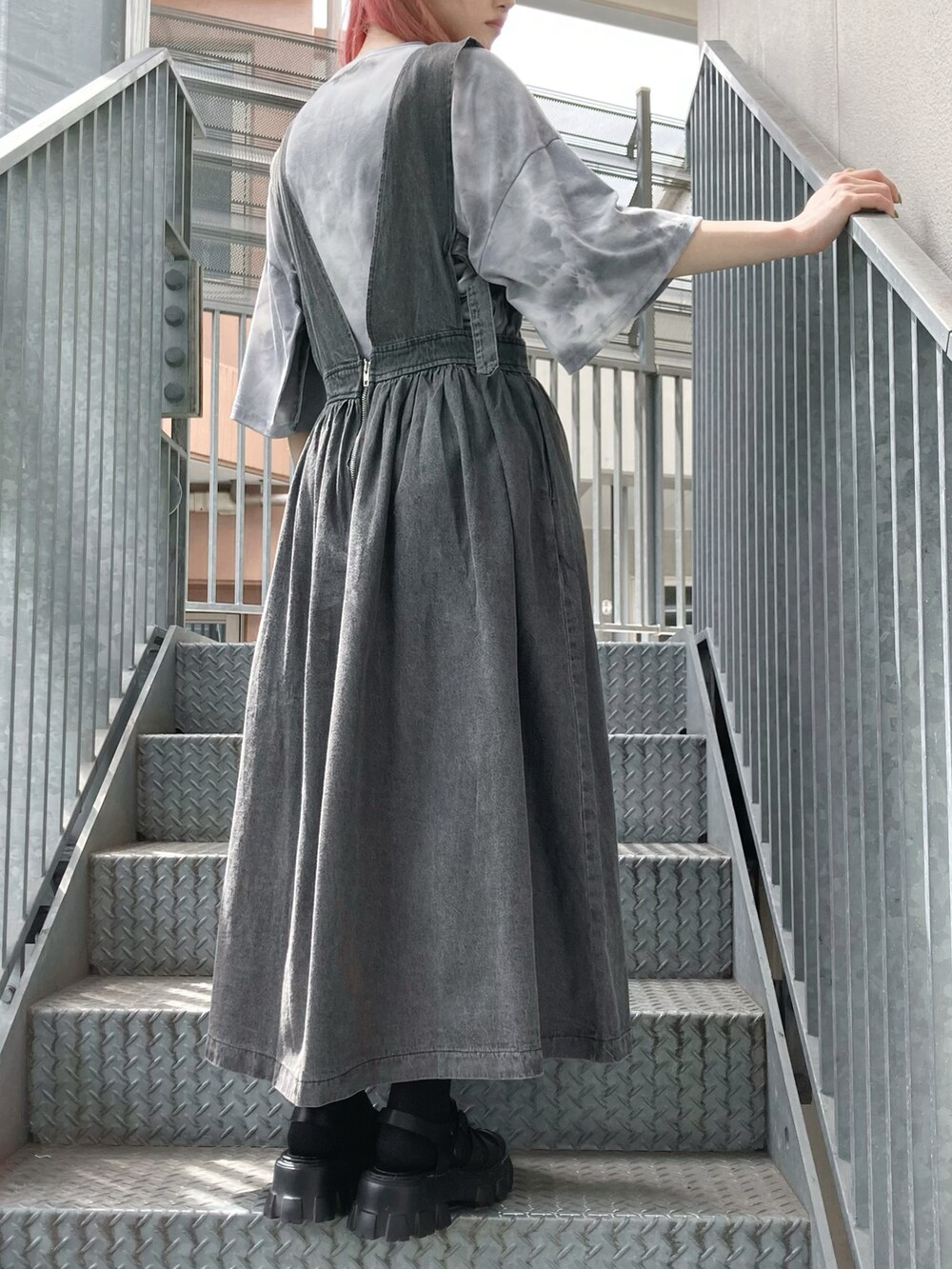 ブラック系のサンダル、ブラック系のジャンパースカート、ブラック系のTシャツ/カットソーを着用したレディースの夏コーディネートの2枚目の写真