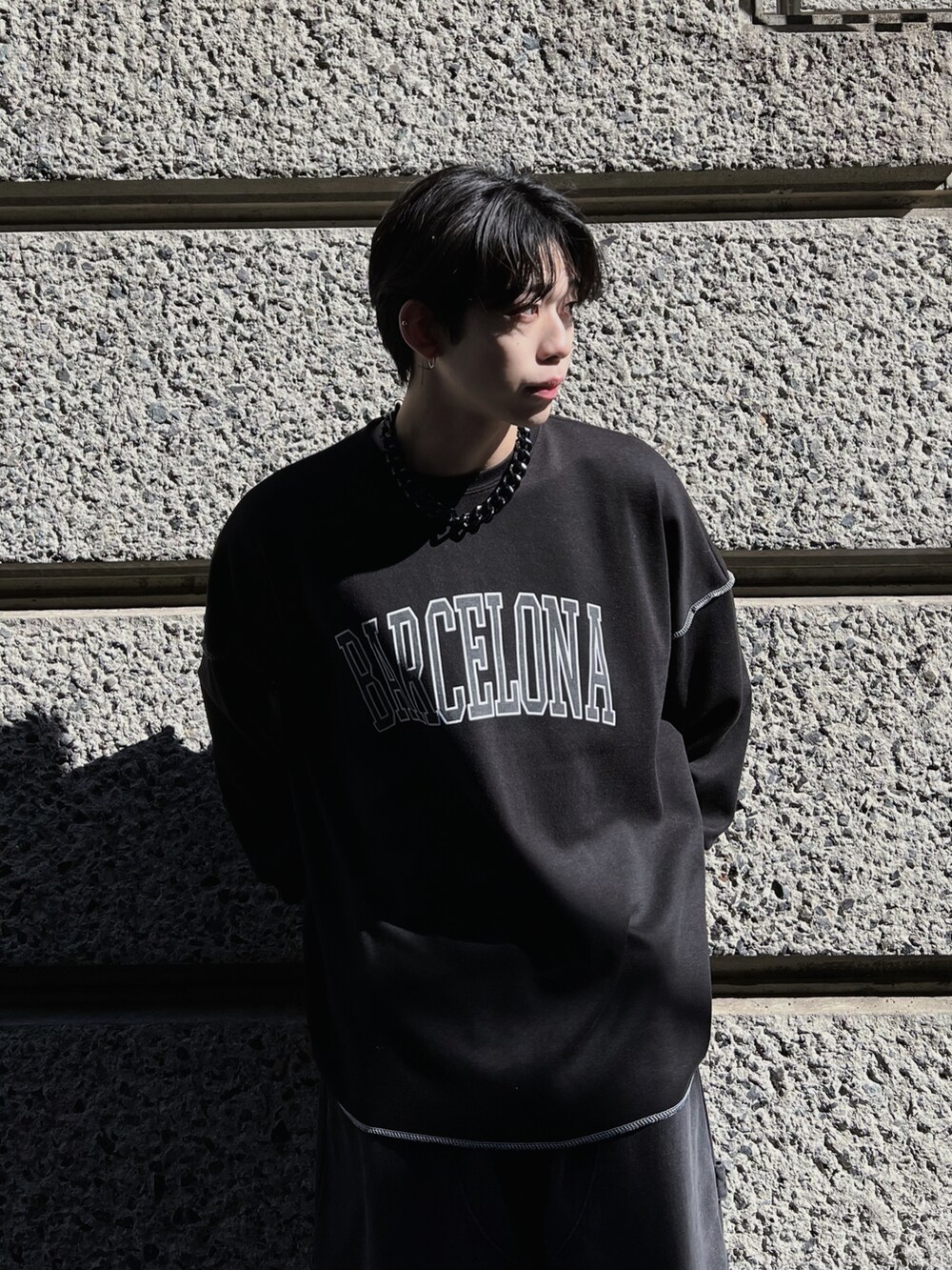 ブラック系のTシャツ/カットソー、ブラック系のスニーカー、ブラック系のデニムパンツを着用したメンズの春コーディネートの2枚目の写真