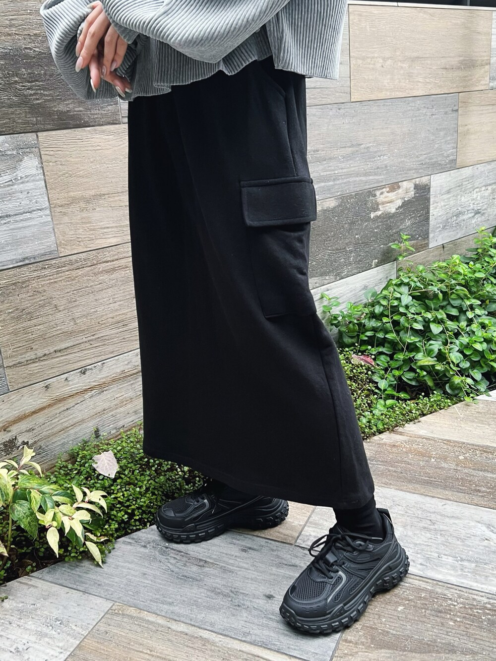 グレー系のパーカー、ブラック系のスカート、ブラック系のスニーカーを着用したレディースの冬コーディネートの3枚目の写真