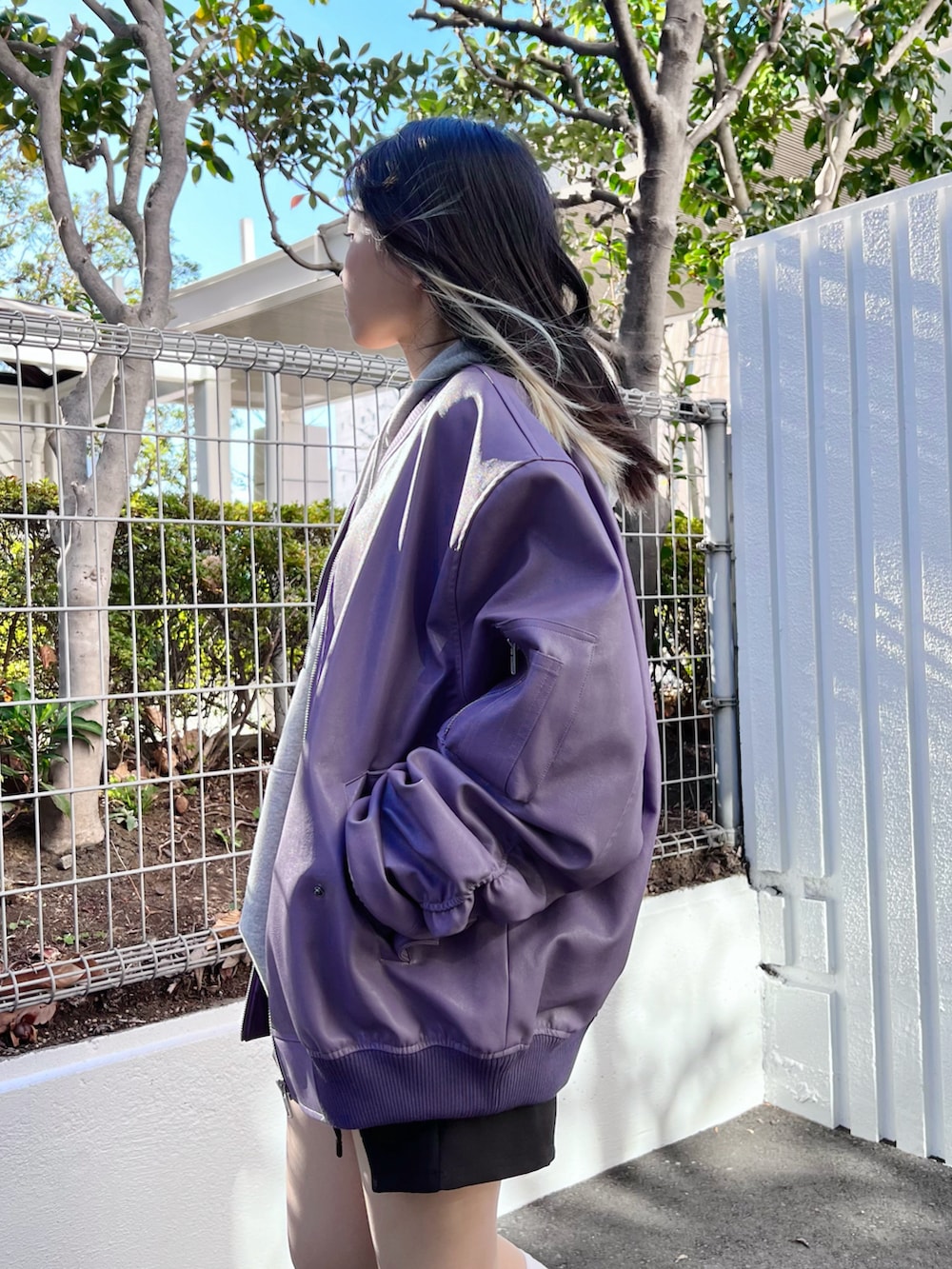 グレー系のパーカー、ブラック系のスカート、パープル系のライダースジャケットを着用したレディースの冬コーディネートの4枚目の写真