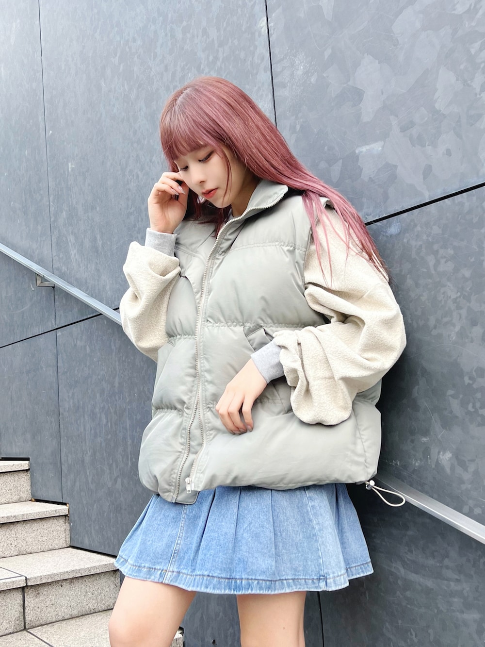 グリーン系のダウンベスト、グレー系のスウェット、ブルー系のデニムスカートを着用したレディースの冬コーディネートの2枚目の写真