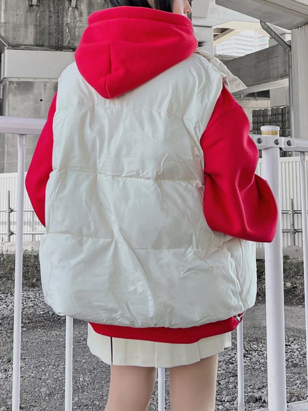 ホワイト系のスニーカー、ホワイト系のベスト、レッド系のパーカーを着用したレディースの冬コーディネートの3枚目の写真