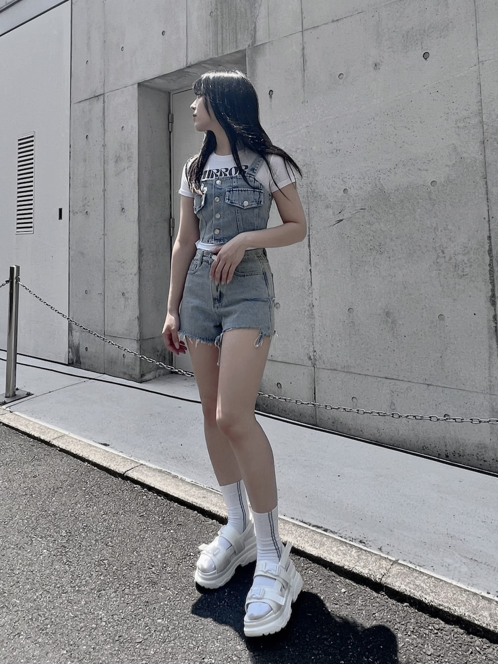 ブルー系のベスト、ブルー系のデニムパンツ、ホワイト系のサンダルを着用したレディースの夏コーディネートの2枚目の写真