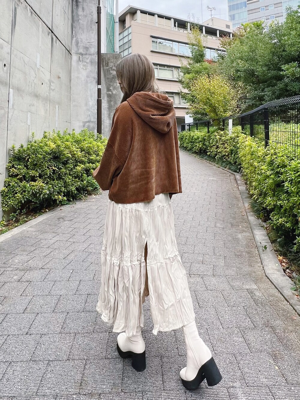 ブラウン系のパーカー、ホワイト系のスカート、ホワイト系のブーツを着用したレディースの冬コーディネートの2枚目の写真