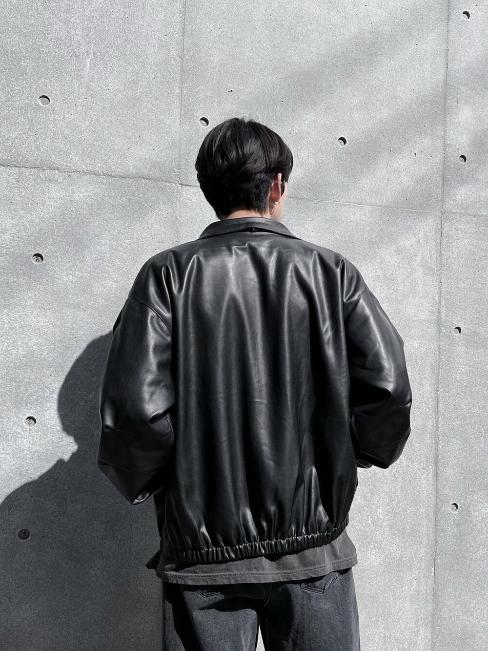 ブラック系のデニムパンツ、ブラック系のブルゾン、グレー系のTシャツ/カットソーを着用したメンズの春コーディネートの3枚目の写真