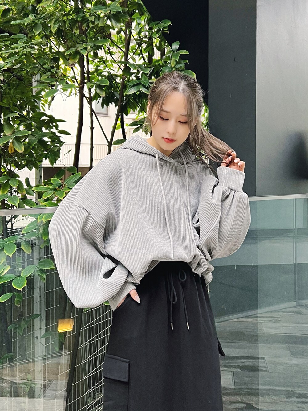 グレー系のパーカー、ブラック系のスカート、ブラック系のスニーカーを着用したレディースの冬コーディネートの2枚目の写真