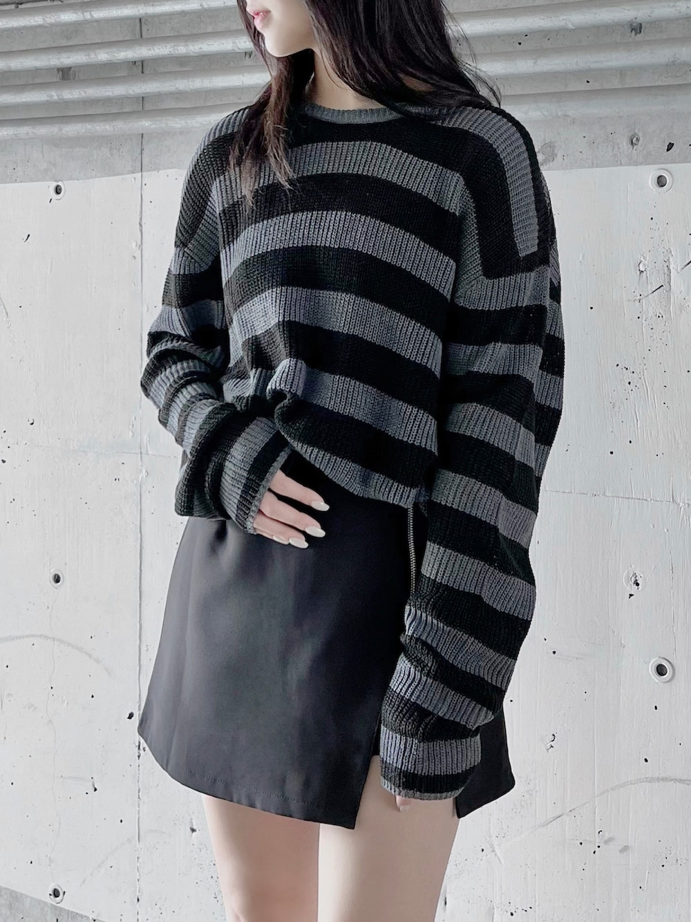 グレー系のニット/セーター、ブラック系のライダースジャケット、ブラック系のスカートを着用したレディースの冬コーディネートの3枚目の写真