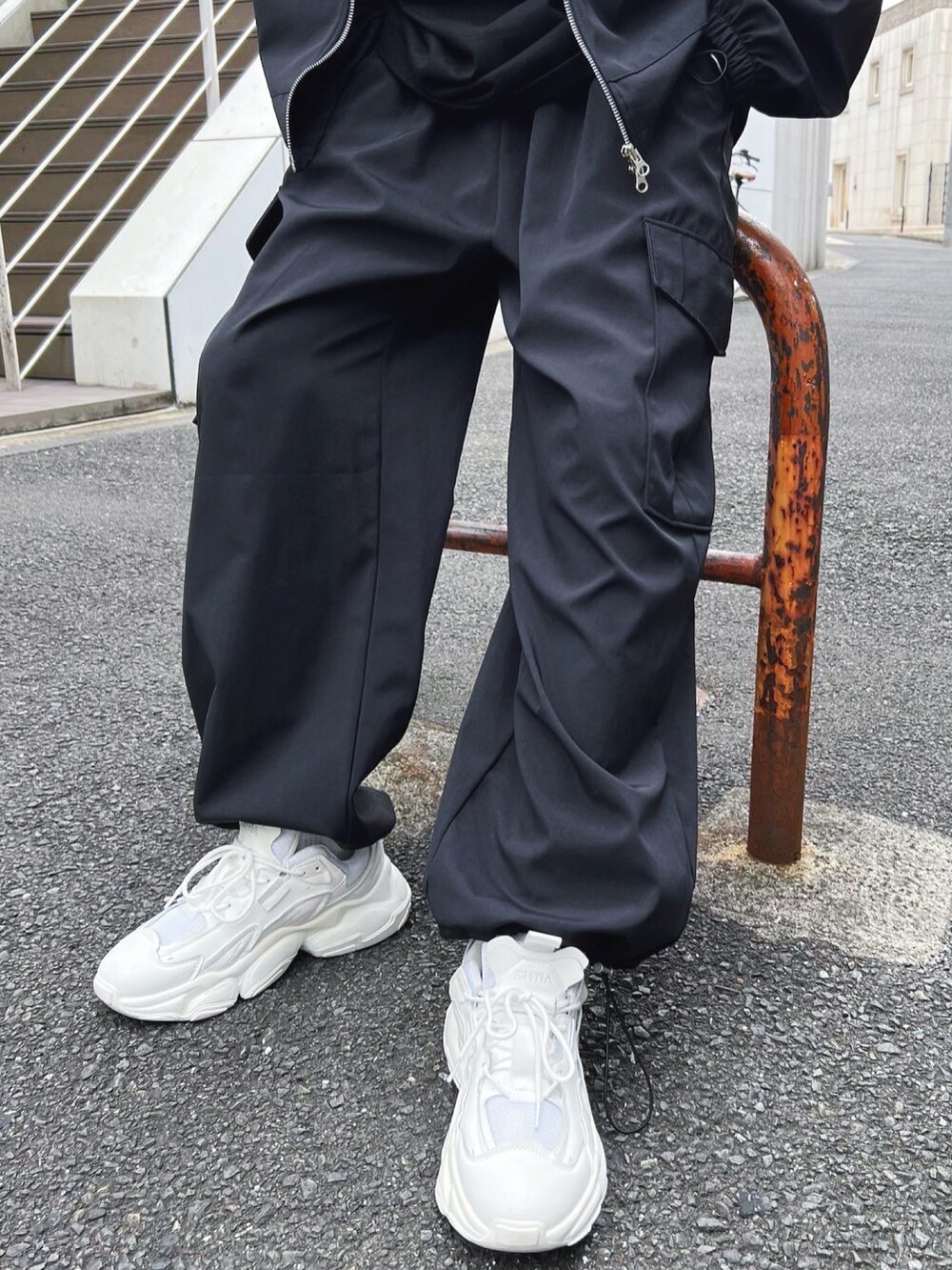 ホワイト系のスニーカー、ブラック系のカーゴパンツ、ブラック系のブルゾンを着用したメンズの秋コーディネートの3枚目の写真