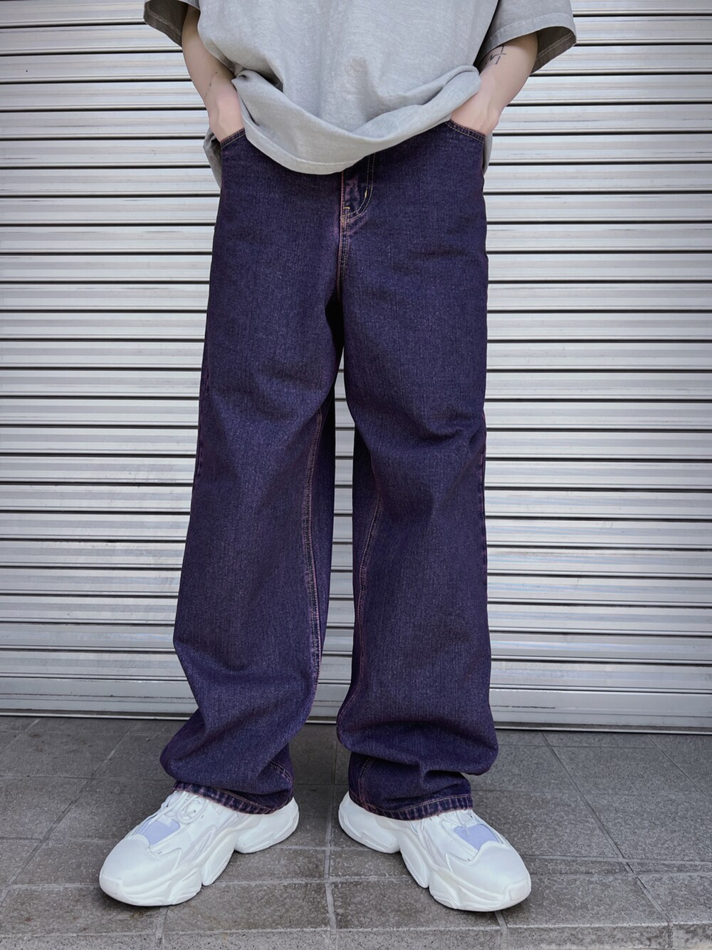 パープル系のデニムパンツ、ホワイト系のスニーカー、シルバー系のショルダーバッグを着用したレディースの春コーディネートの4枚目の写真