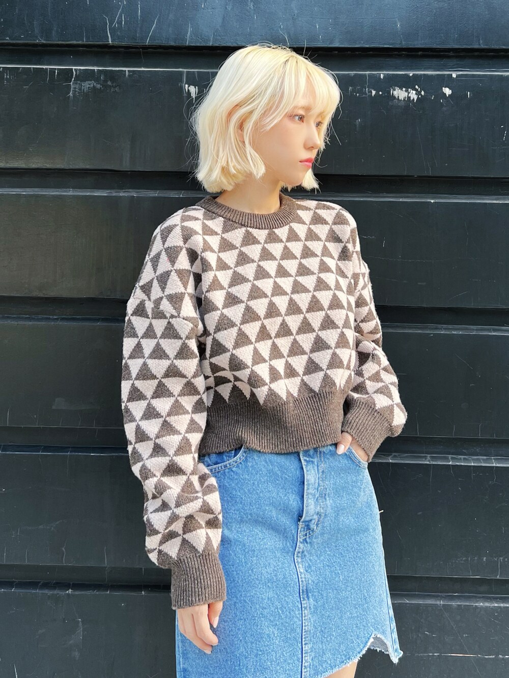 ホワイト系のダウンベスト、ブラウン系のニット/セーター、ブルー系のデニムスカートを着用したレディースの冬コーディネートの4枚目の写真