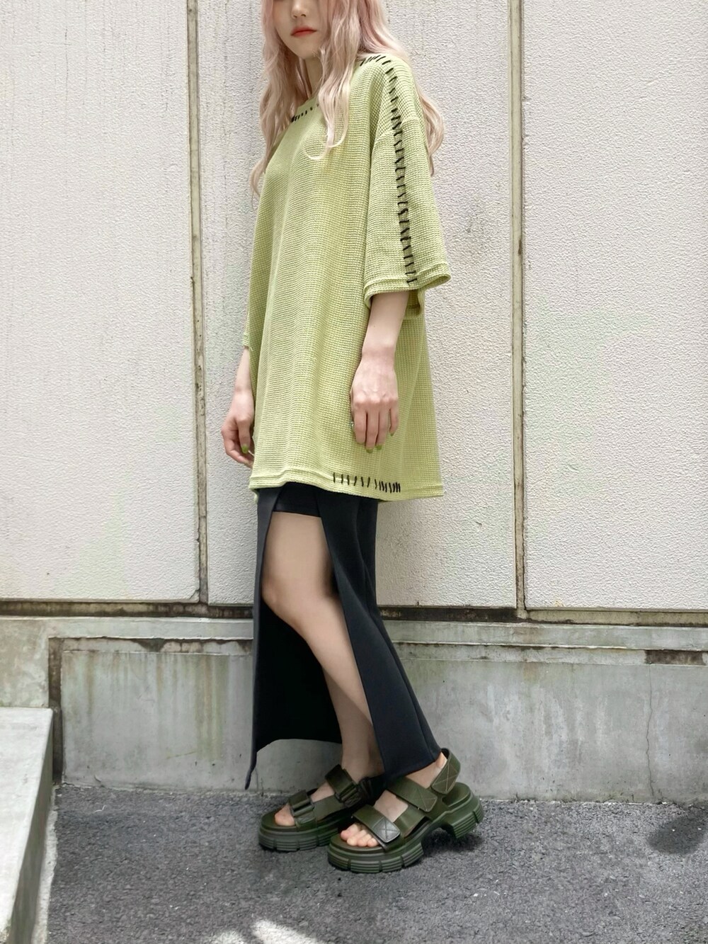 グリーン系のニット/セーター、ブラック系のスカート、ブラック系のトートバッグを着用したレディースの夏コーディネートの2枚目の写真