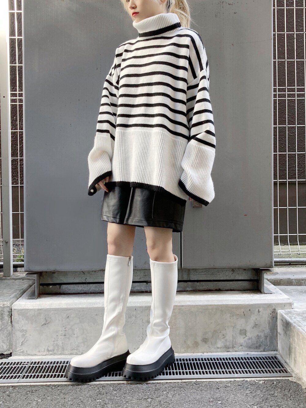 ホワイト系のブーツ、ブラック系のその他パンツ、ホワイト系のニット/セーターを着用したレディースの冬コーディネートの2枚目の写真