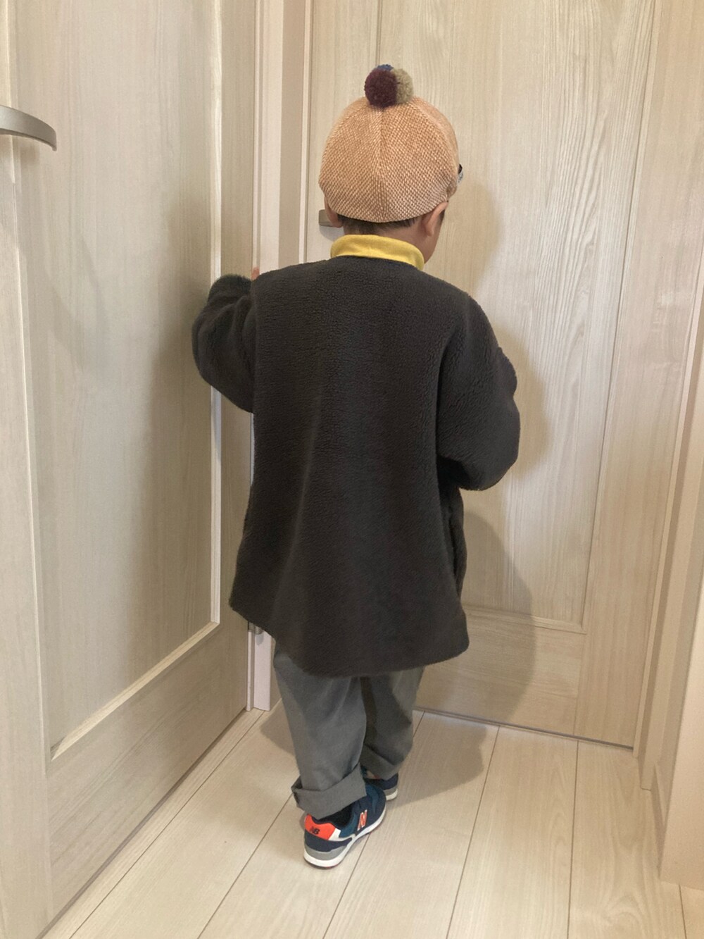 グレー系のノーカラーコート、グレー系のパンツ、ブルー系のスニーカーを着用したキッズの冬コーディネートの3枚目の写真