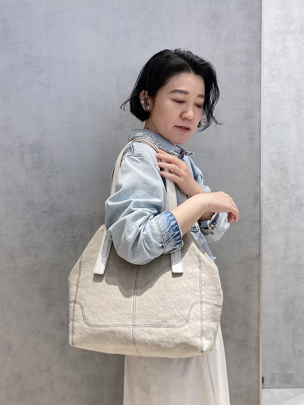 ベージュ系のトートバッグ、シルバー系のイヤリング、シルバー系のイヤリングを着用したレディースの春コーディネートの3枚目の写真