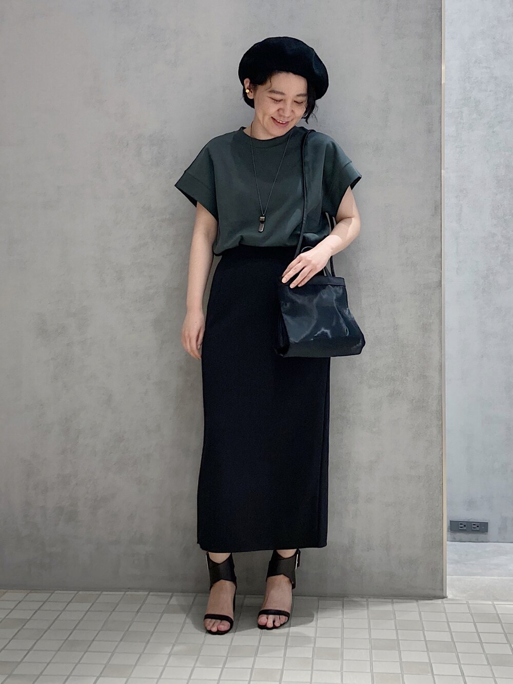 ブラック系のショルダーバッグ、ゴールド系のイヤリングを着用したレディースの春コーディネートの2枚目の写真