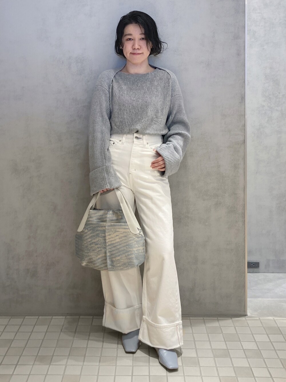 ベージュ系のハンドバッグ、シルバー系のイヤリングを着用したレディースの春コーディネートの2枚目の写真