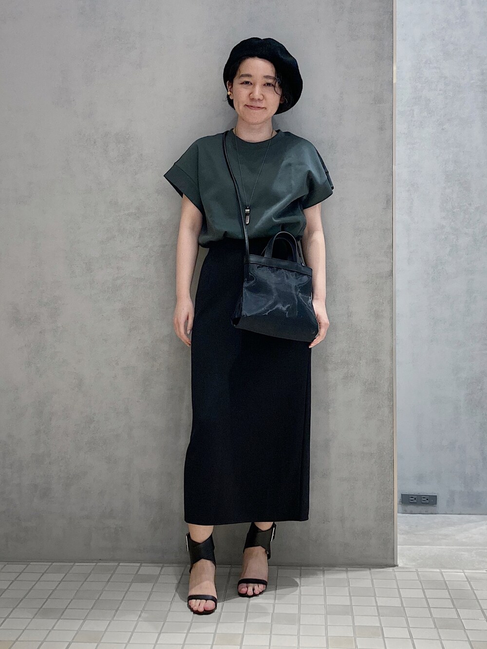 ブラック系のショルダーバッグ、ゴールド系のイヤリングを着用したレディースの春コーディネートの3枚目の写真