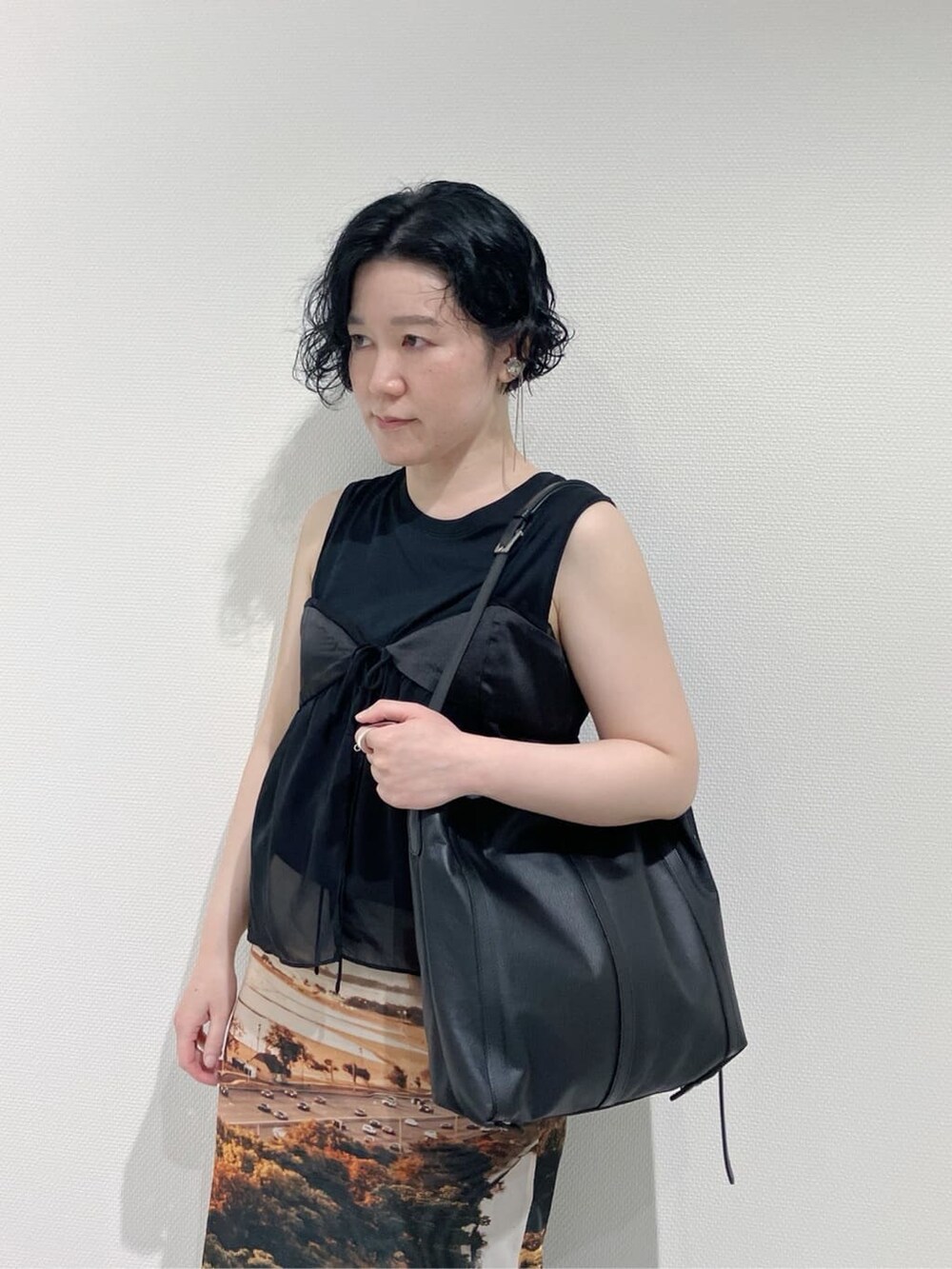 ブラック系のショルダーバッグ、シルバー系のリングを着用したレディースの夏コーディネートの3枚目の写真