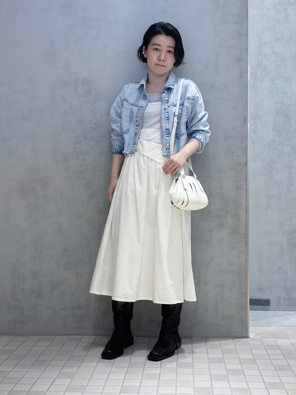 ホワイト系のハンドバッグ、シルバー系のイヤリング、シルバー系のイヤリングを着用したレディースの春コーディネートの2枚目の写真