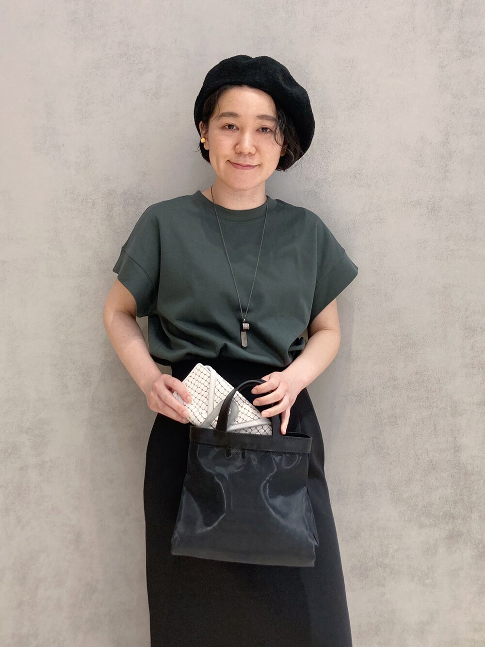 ブラック系のショルダーバッグ、ゴールド系のイヤリングを着用したレディースの春コーディネートの4枚目の写真