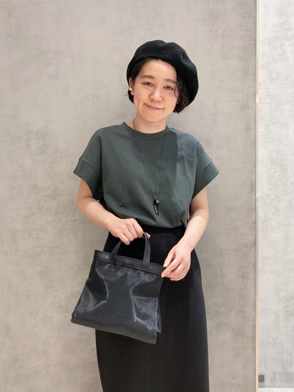 ブラック系のショルダーバッグ、ゴールド系のイヤリングを着用したレディースの春コーディネートの5枚目の写真