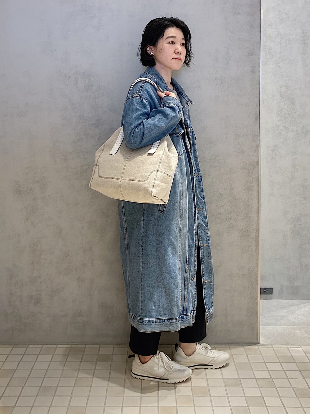 ベージュ系のトートバッグ、シルバー系のイヤリングを着用したレディースの春コーディネートの2枚目の写真