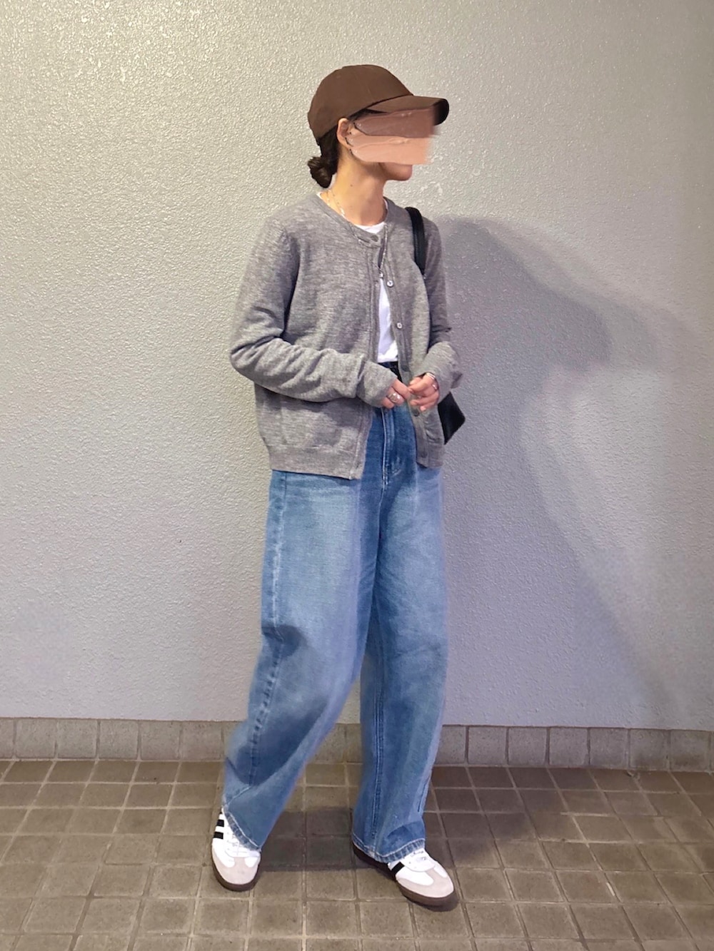 ブルー系のデニムパンツ、ホワイト系のスニーカー、グレー系のカーディガン/ボレロを着用したレディースの冬コーディネートの2枚目の写真