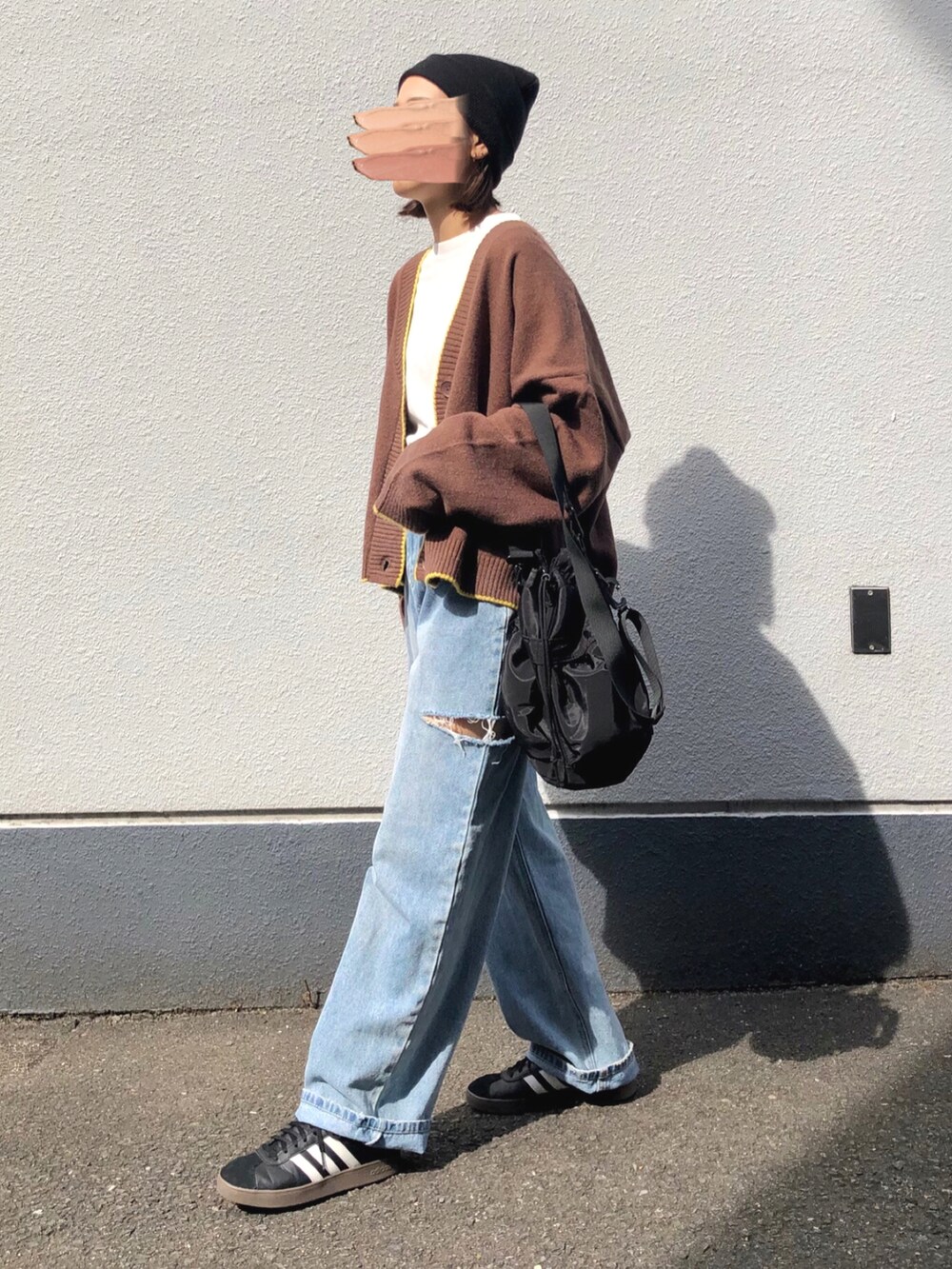 ブラウン系のカーディガン/ボレロ、ブラック系のバッグ、ブルー系のデニムパンツを着用したレディースの春コーディネートの2枚目の写真