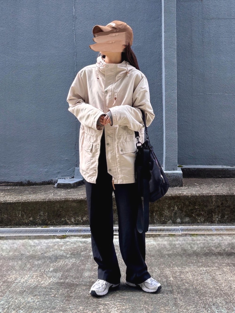 ホワイト系のマウンテンパーカー、ブラック系のスラックス、グレー系のニット/セーターを着用したレディースの春コーディネートの3枚目の写真