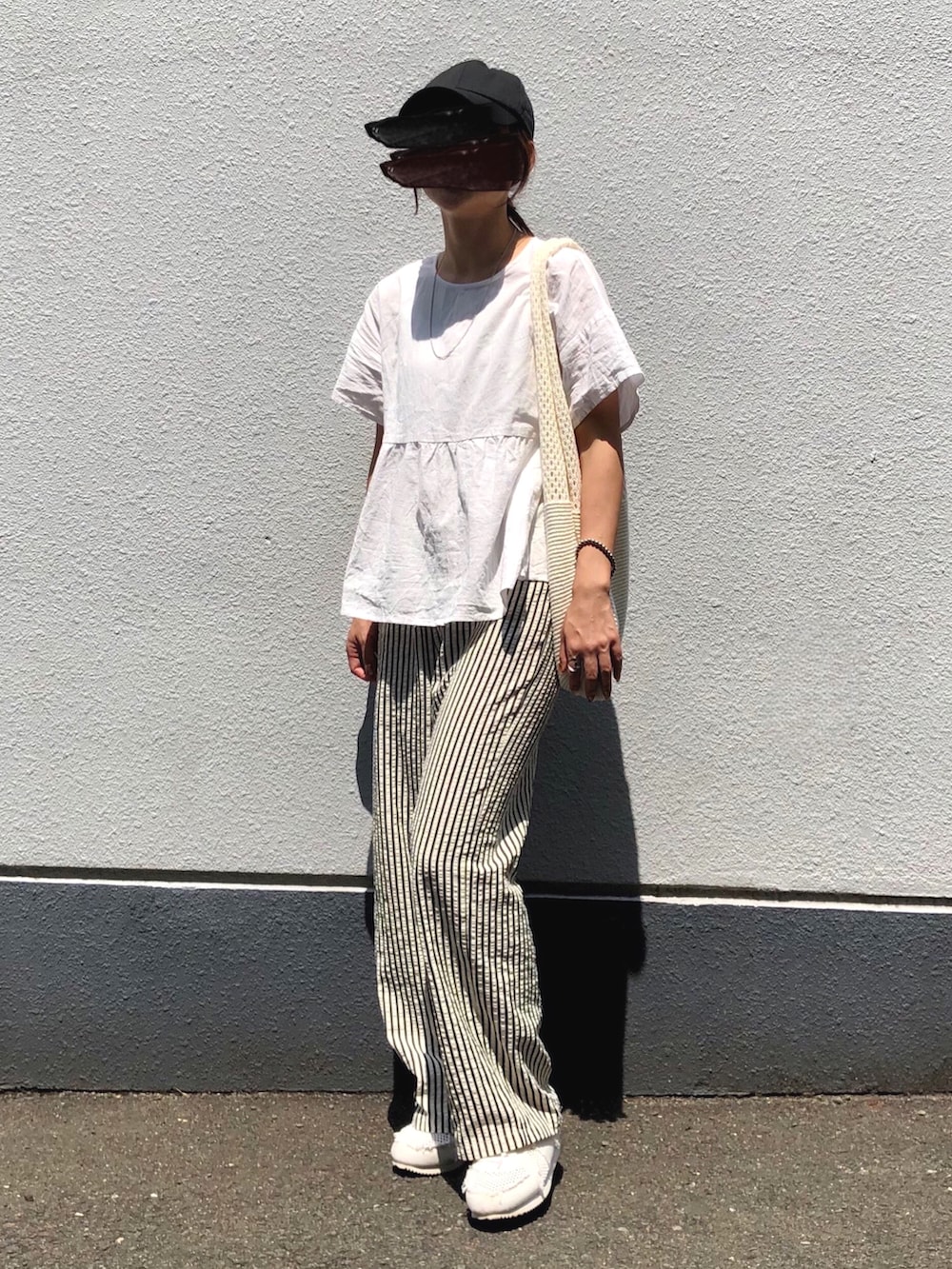 ホワイト系のスニーカー、ブラウン系のバッグを着用したレディースの夏コーディネートの2枚目の写真