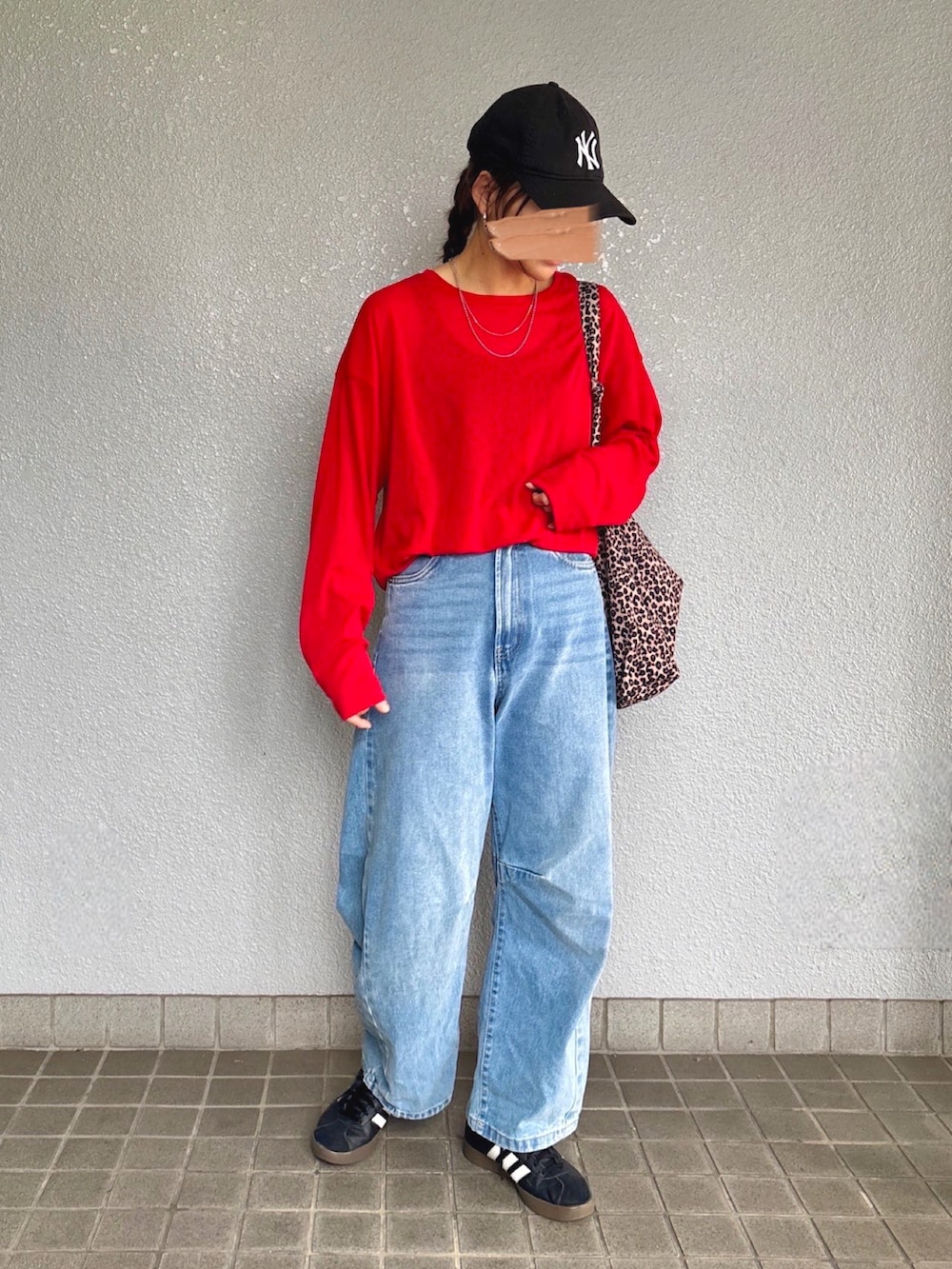 レッド系のTシャツ/カットソー、ブラック系のスニーカー、ブルー系のデニムパンツを着用したレディースの秋コーディネートの2枚目の写真