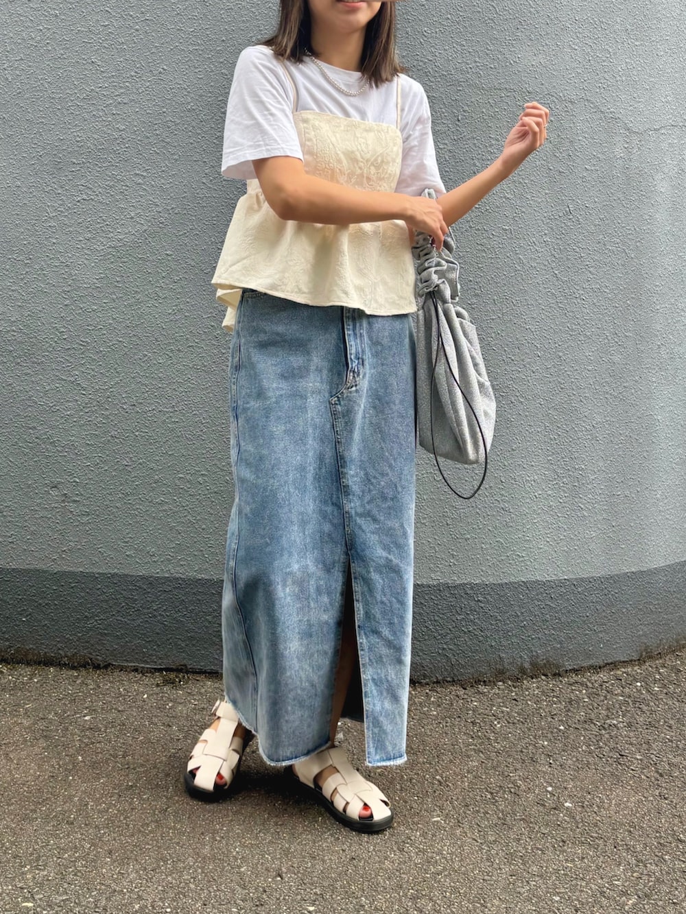 ホワイト系のショルダーバッグ、ブルー系のデニムスカート、ベージュ系のサンダルを着用したレディースの秋コーディネートの2枚目の写真