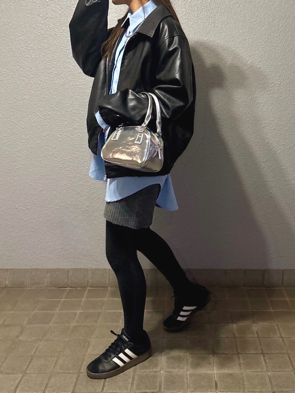 グレー系のスカート、シルバー系のボストンバッグ、ブラック系のスニーカーを着用したレディースの春コーディネートの2枚目の写真