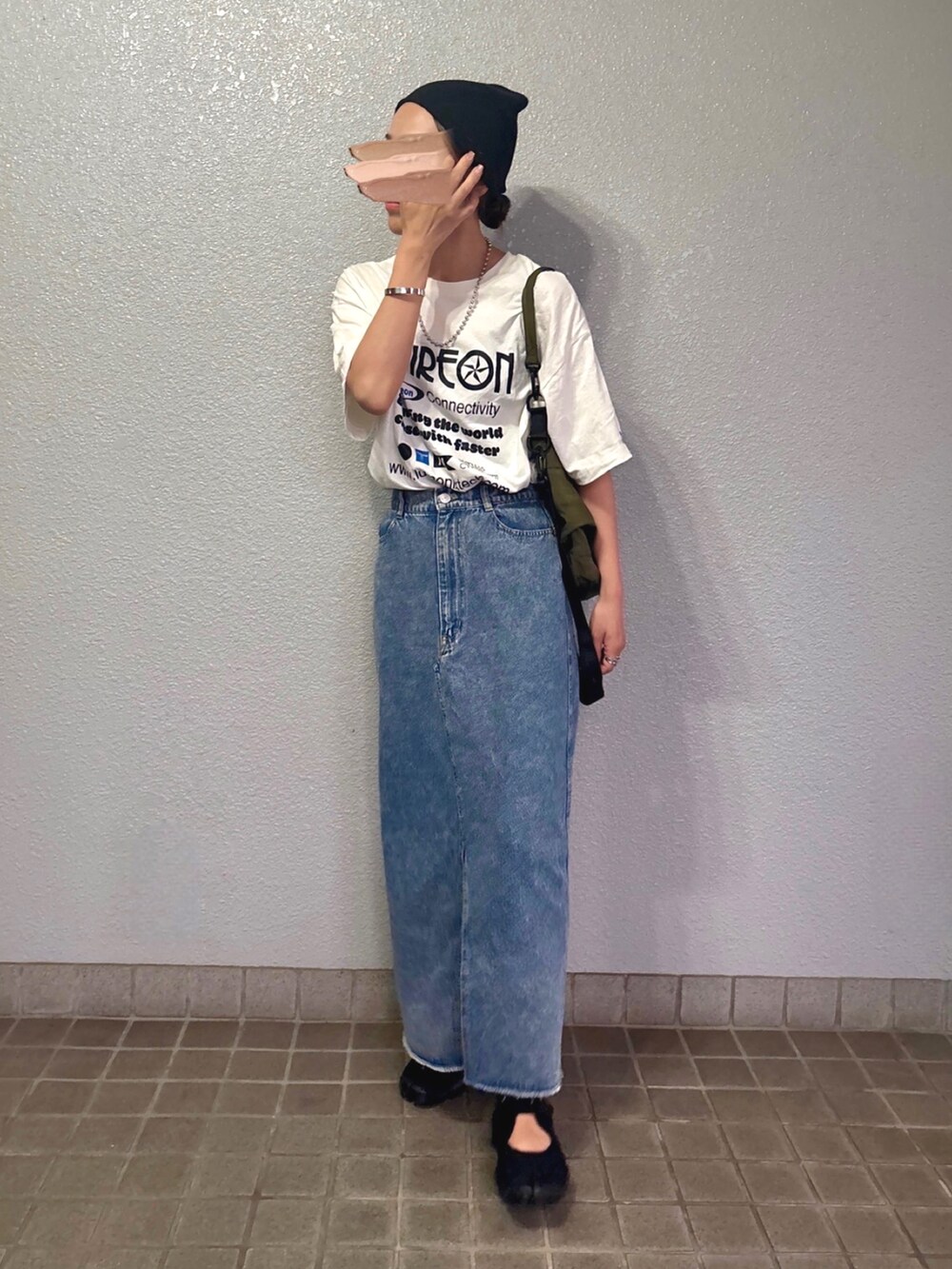 ホワイト系のTシャツ/カットソー、ブラック系のスニーカー、ブルー系のデニムスカートを着用したレディースの夏コーディネートの2枚目の写真