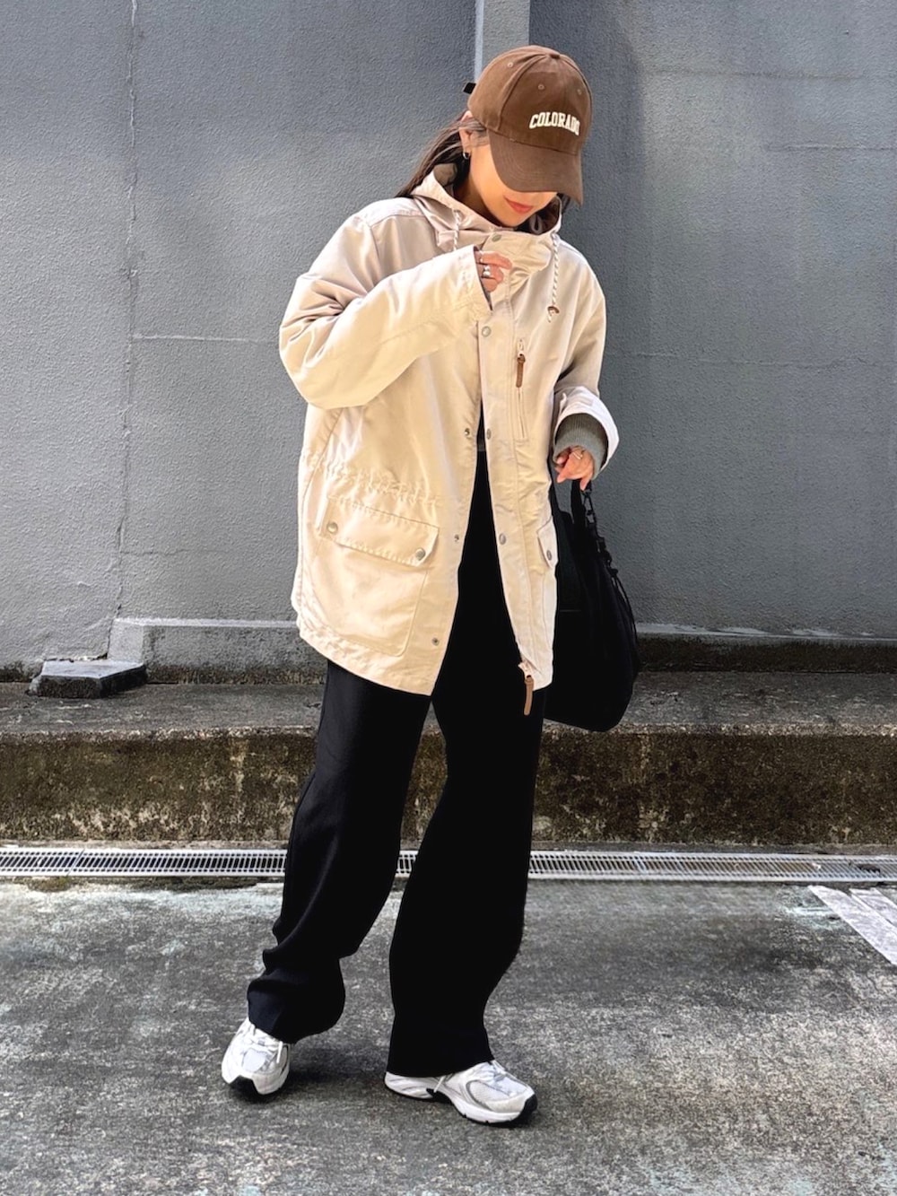 ホワイト系のマウンテンパーカー、ブラック系のスラックス、グレー系のニット/セーターを着用したレディースの春コーディネートの2枚目の写真