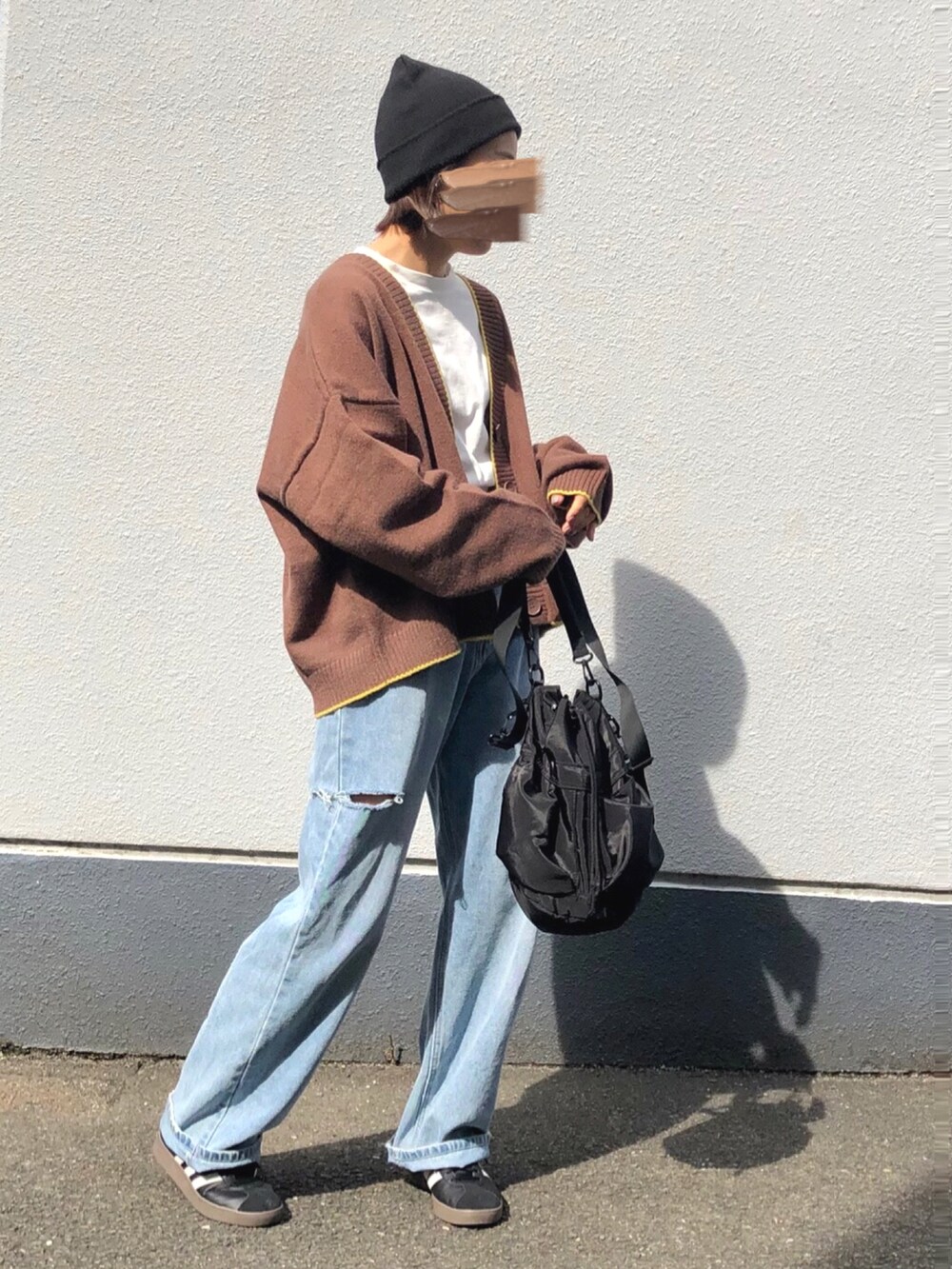 ブラウン系のカーディガン/ボレロ、ブラック系のバッグ、ブルー系のデニムパンツを着用したレディースの春コーディネートの3枚目の写真