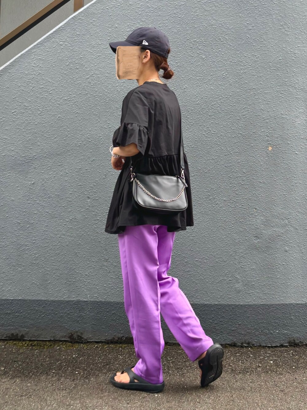 ブラック系のトップス、パープル系のスラックス、ブラック系のサンダルを着用したレディースの夏コーディネートの2枚目の写真